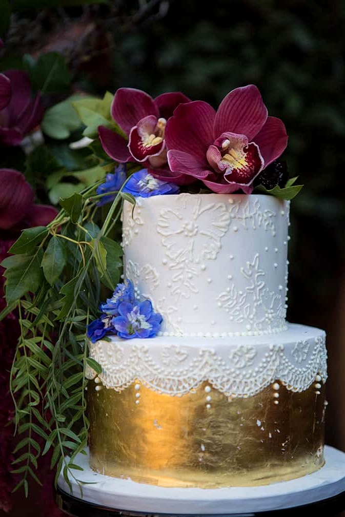White fondant wedding cake with gold foil and burgundy orchids | Lola Images