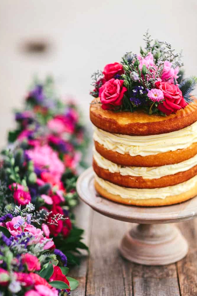 Naked wedding cake with bright floral topper