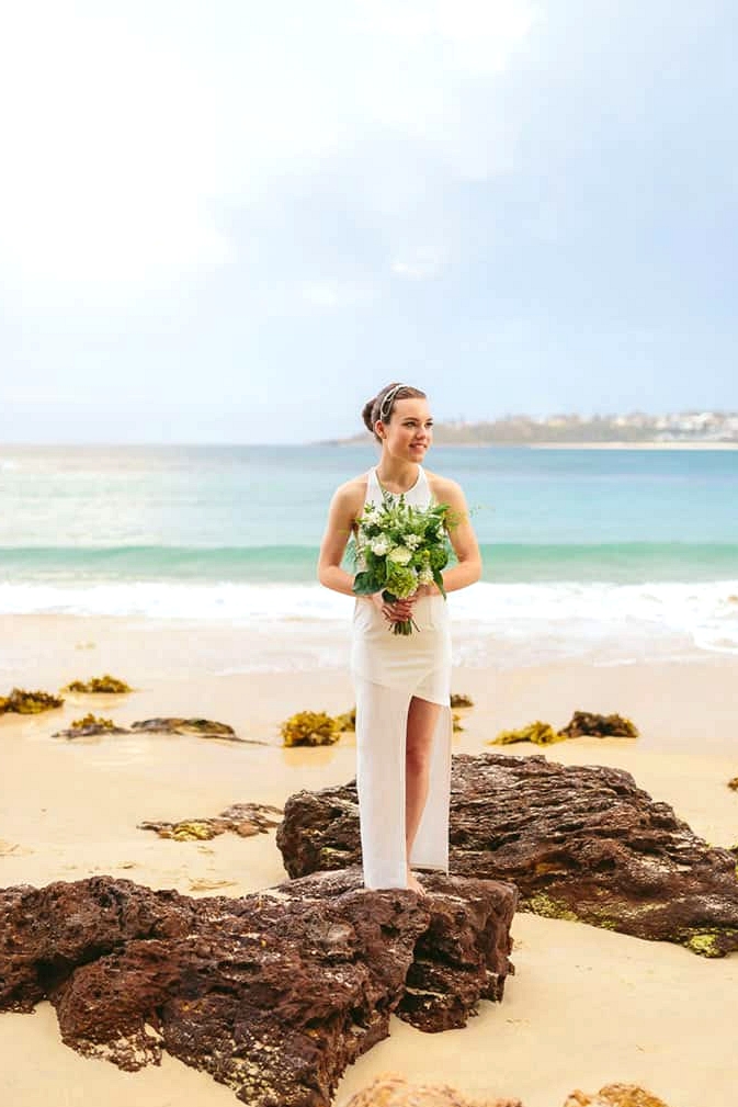 Modern beach bride holding green and white wedding bouquet