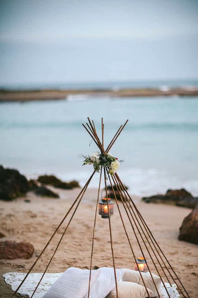 Beach wedding teepee with lanterns and pillow cushions