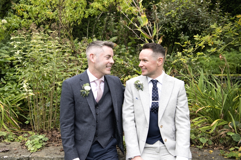 Eoin & Darran Real Wedding grooms smiling exterior sitting green