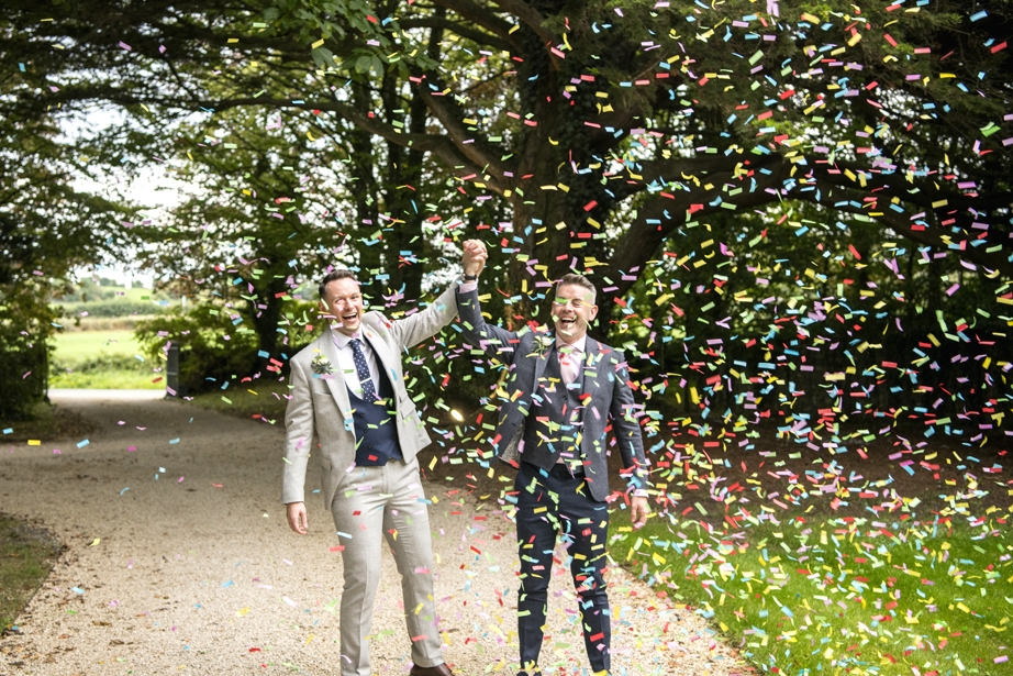 Eoin & Darran Real Wedding confetti couple holding hands exterior path shot laughing smiling