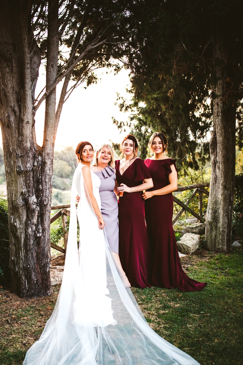bride with cathedral veil stands with mother and bridesmaids at destination wedding