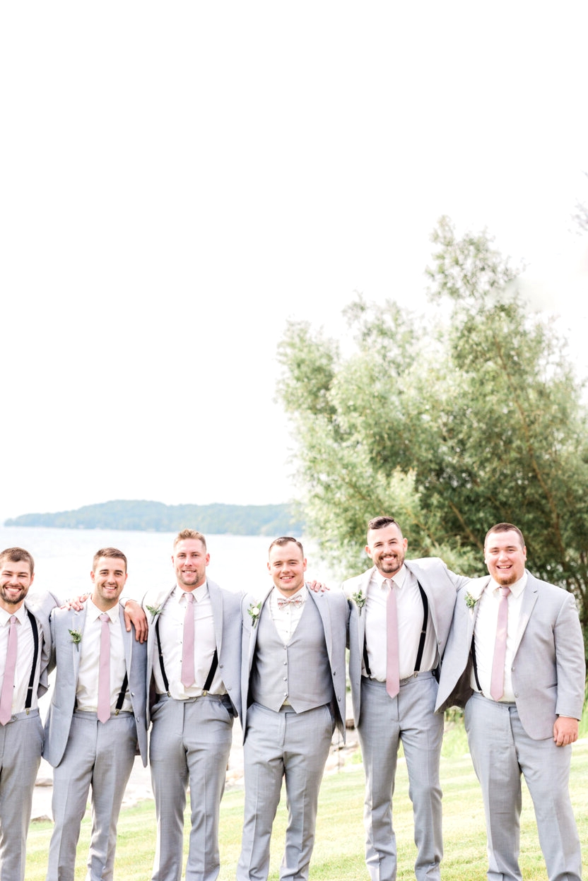 Groomsmen on their own groom laughing sea field grass exterior