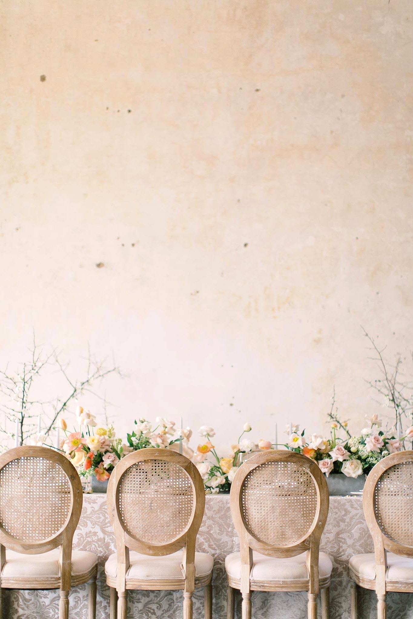 spring wedding table with cane back dining chairs and yellow and cream floral arrangements