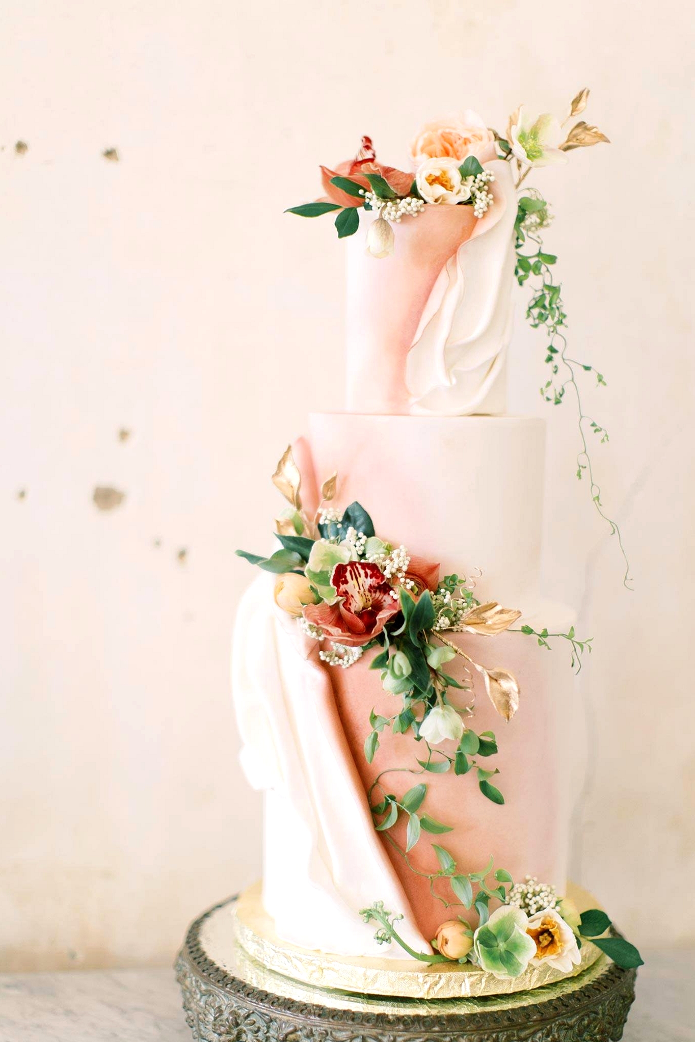 draped fondant wedding cake with pink and white colors and fresh trailing flowers