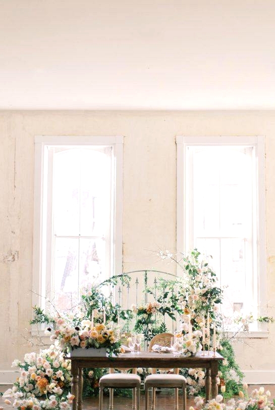 sweetheart table with box flower floor arrangements and a floralized gate backdrop