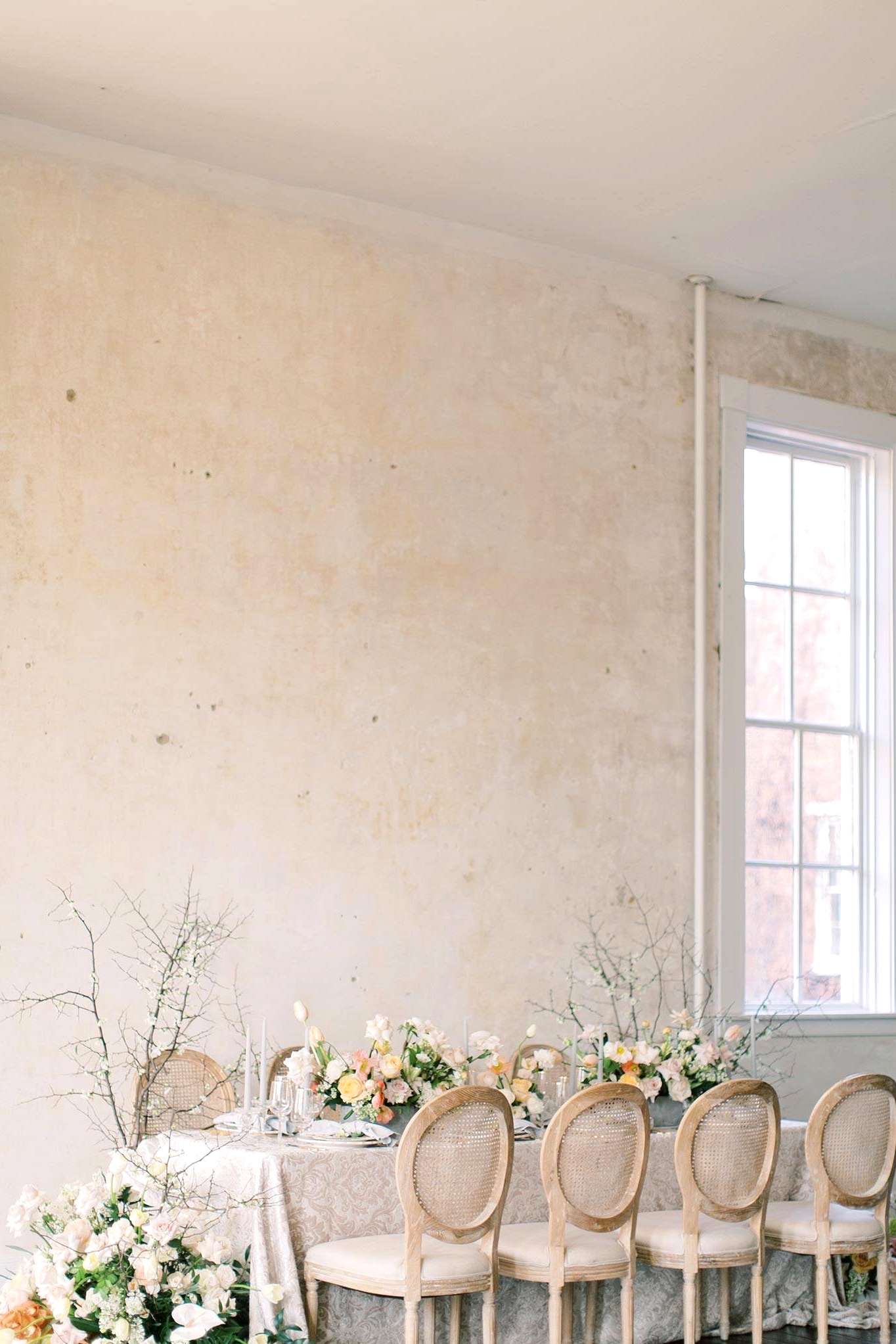 spring wedding table with cane back dining chairs and yellow and cream floral arrangements