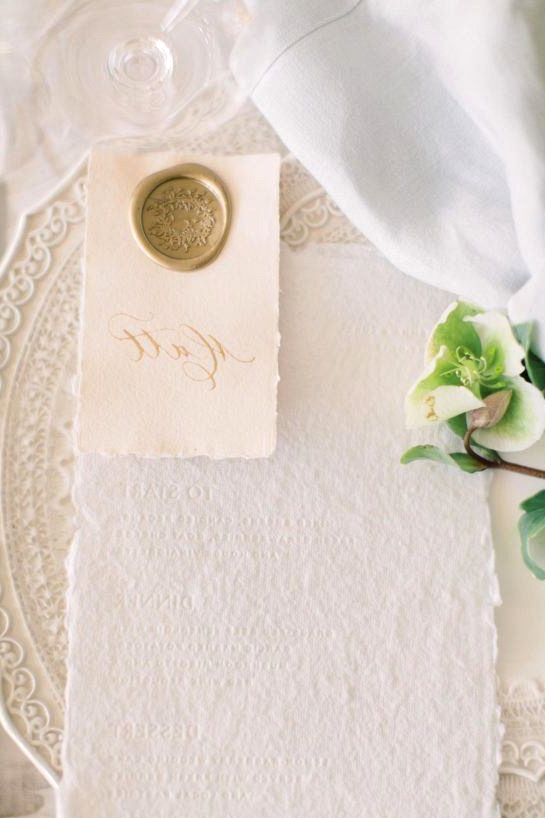 white letterpress menu with a calligraphed place card with a gold wax seal