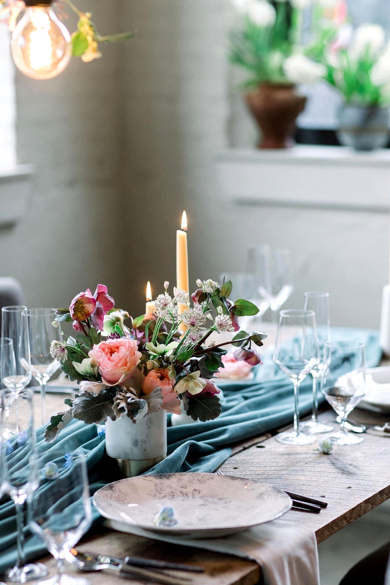 cozy white brick wedding reception with potted plants, a floral canopy and velvet teal table runner