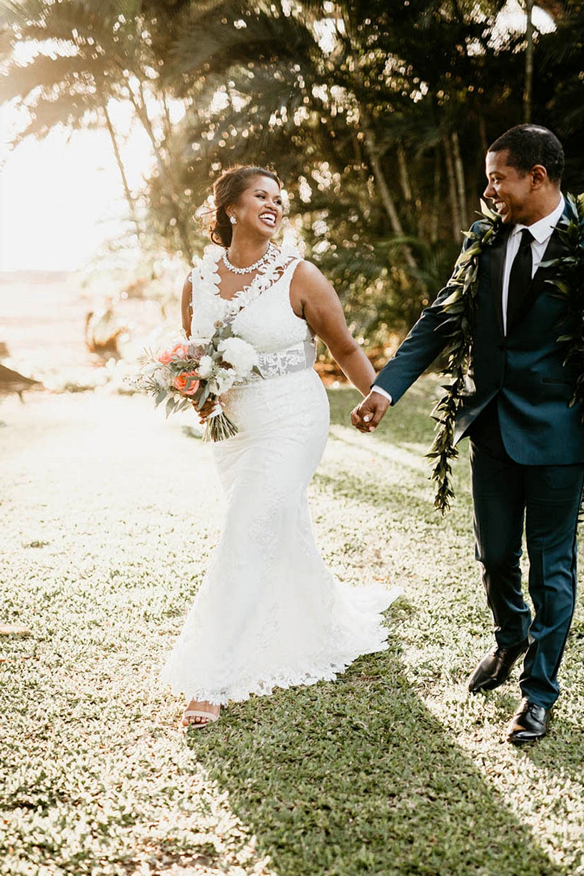 Maui wedding couple portraits beneath palm trees with bride in a v-neck wedding dress and groom with a traditional Hawaiian lei