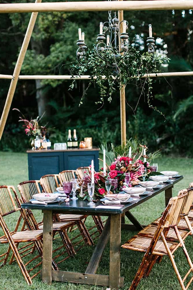 Bohemian berry outdoor wedding reception setting with a greenery draped chandelier | Camilla Kirk Photography