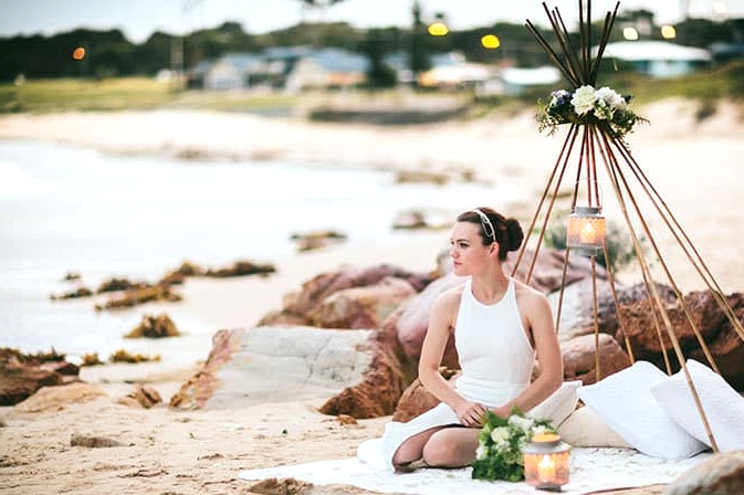 Modern bride sitting in beach wedding teepee