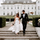 Exterior bride and groom walking down hotel steps flowers holding pink roses bouquet
